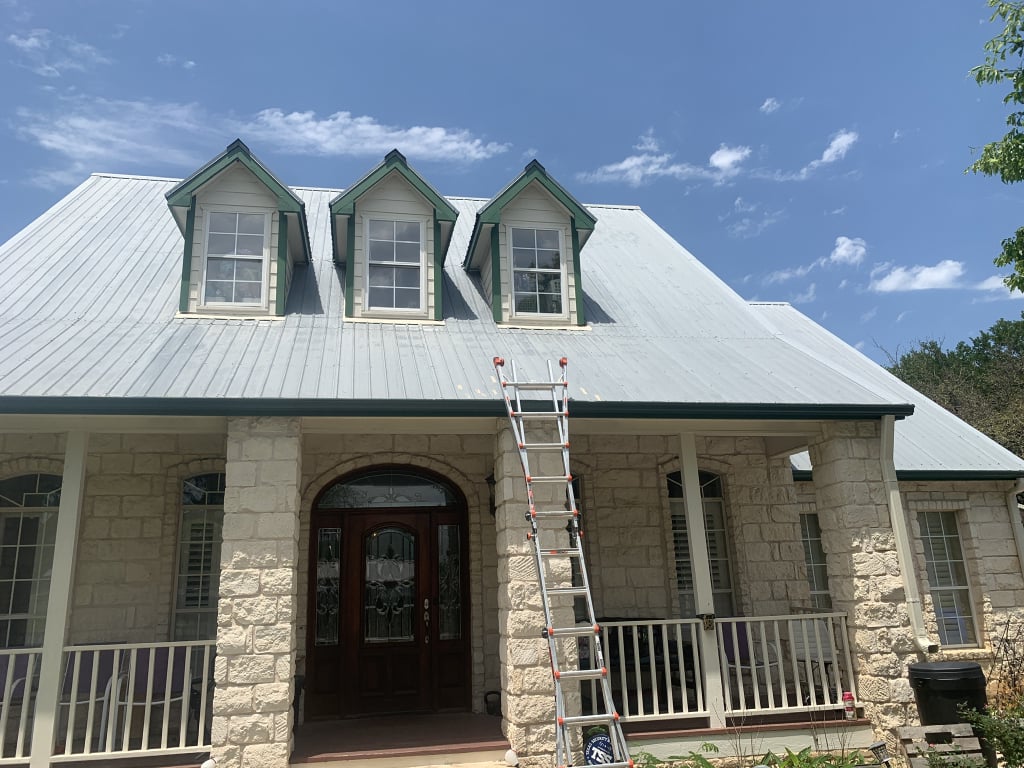 Metal roof with three dormers above a stone-front porch