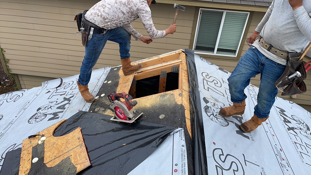 Roofers exposing decking beneath shingles during a roof repair