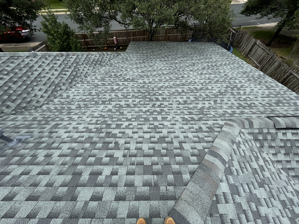 Close view of intersecting shingle roof planes and a capped hip