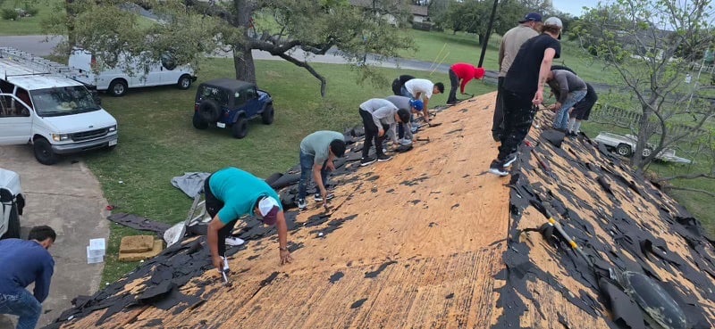 Roofing crew removing shingles and preparing a residential roof